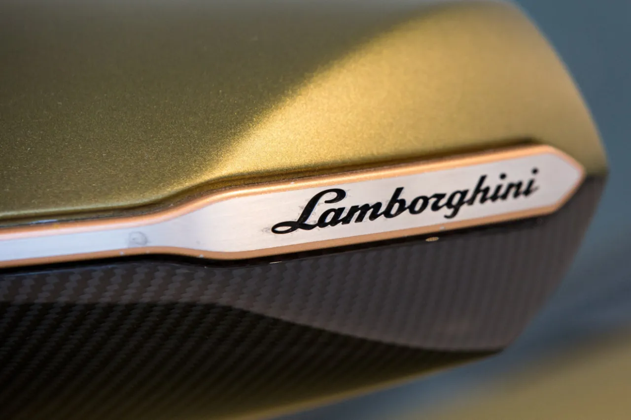 Złote Lamborghini, marka stworzona przez Ferruccio, z logo na karbonowym elemencie.