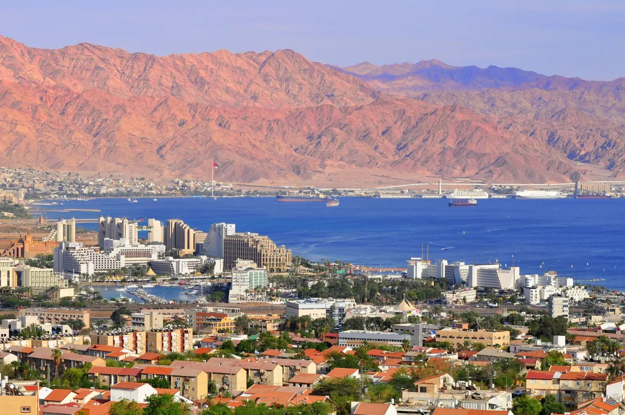 Widok na Eilat w Izraelu, z górami w tle. Czy jest bezpiecznie? Miasto tętni życiem, port pełen statków, a morze zaprasza do wypoczynku.