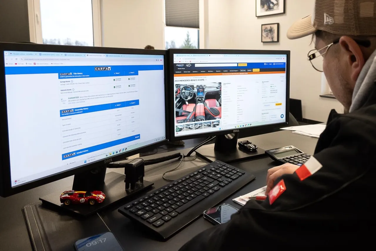 Mężczyzna sprawdza historię pojazdu na ekranie komputera, aby dowiedzieć się, jak sprawdzić auto z USA. Widoczne raporty CARFAX.