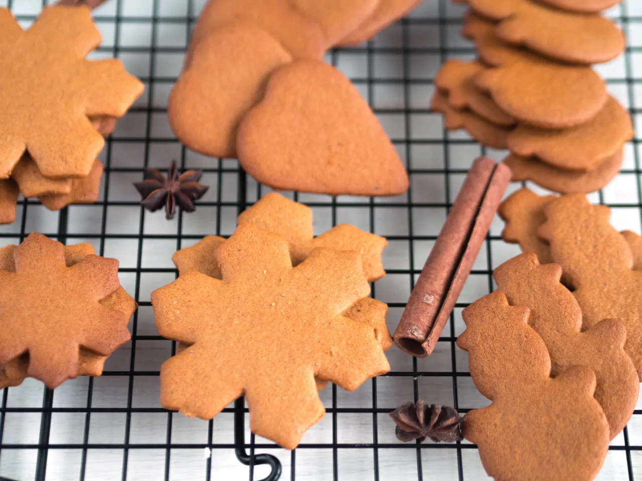 Bezglutenowe pierniki w kształcie gwiazdek i serc, przypominające o świątecznym przepisie. Obok laska cynamonu i anyż.