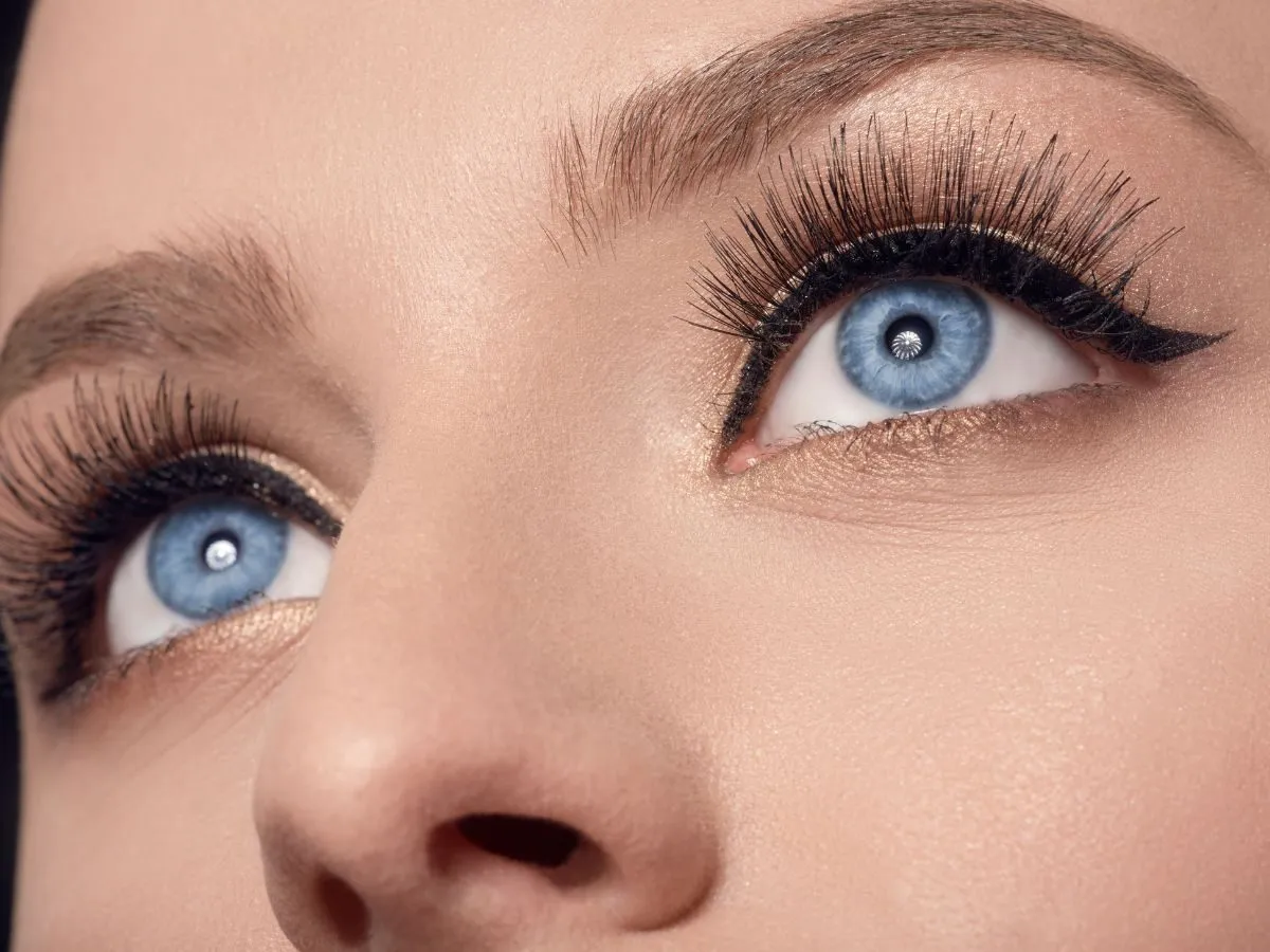 kobieta w ciąży malująca rzęsy tuszem, szczęśliwa