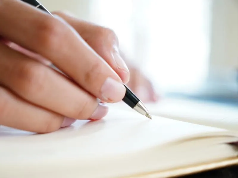 osoba pisząca dedykację w książce, elegancki długopis, otwarte dłonie z książką