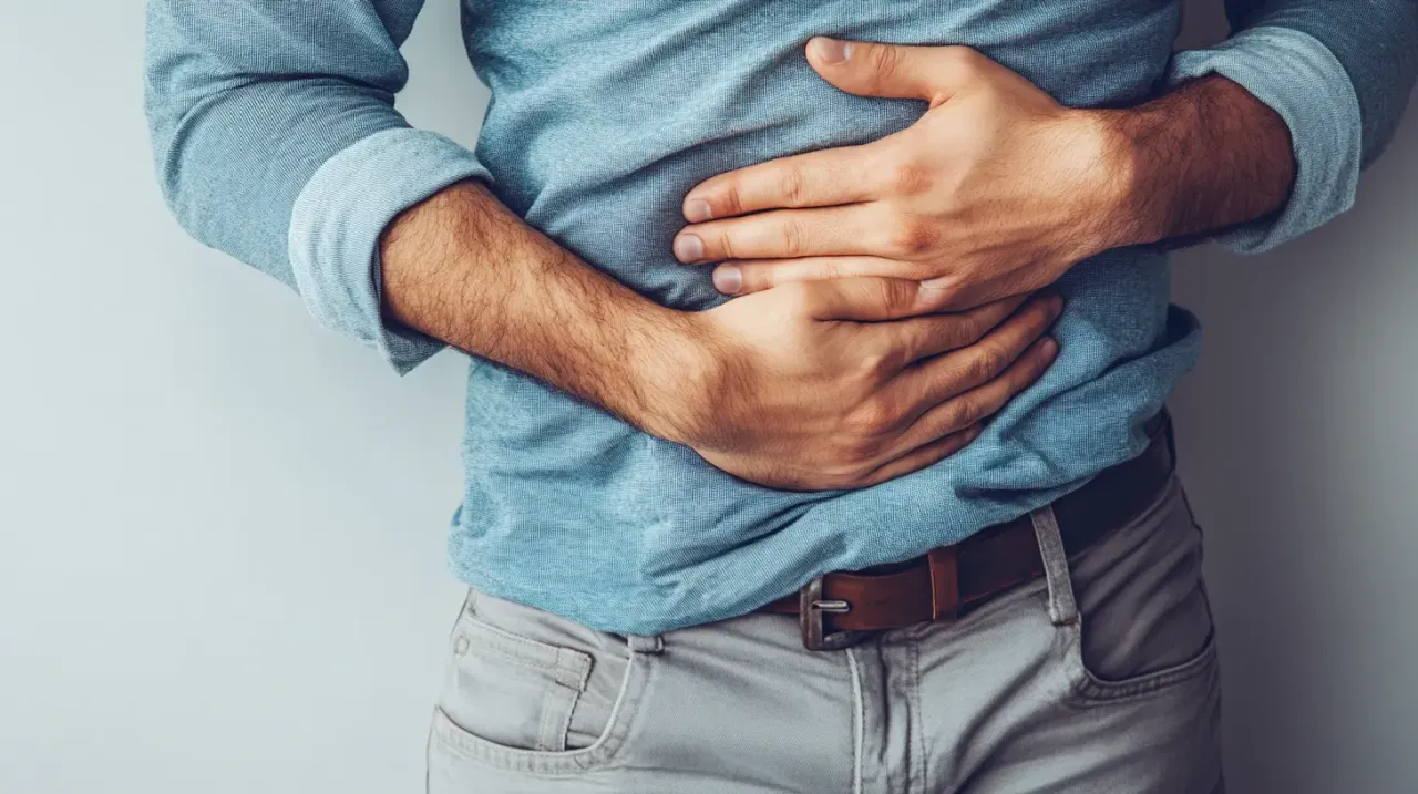 Mężczyzna trzyma się za brzuch, szukając ulgi w b&oacute;lu. Co na b&oacute;l brzucha?