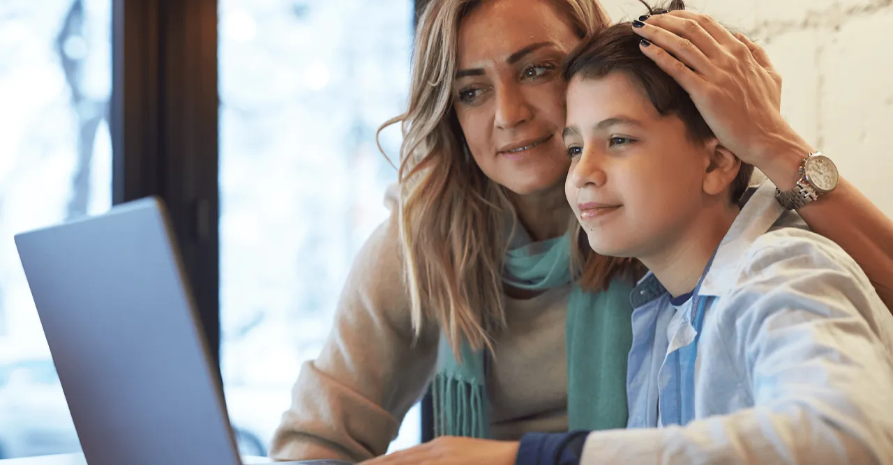 Rodzice z dziećmi korzystający z laptopa, uśmiechnięci, w domowym otoczeniu