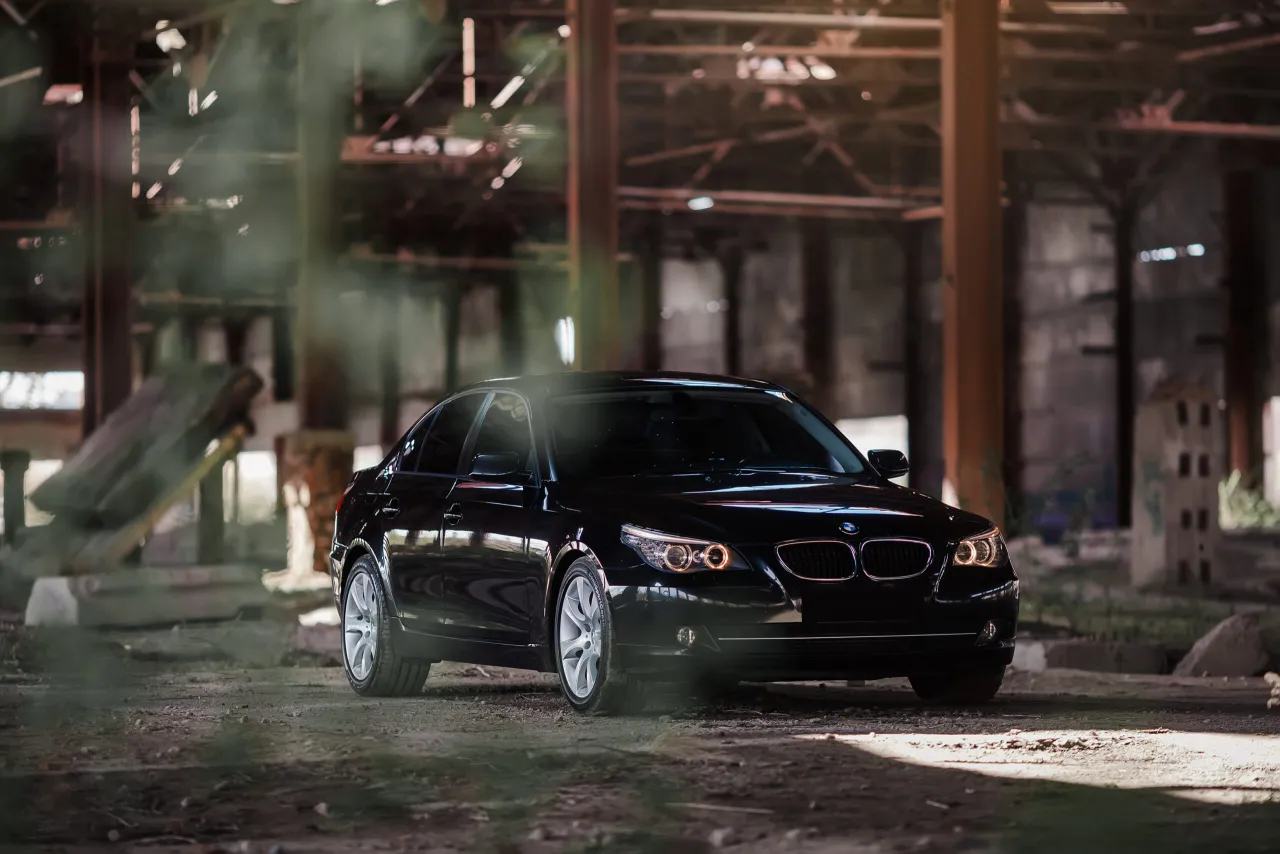 Czarny BMW E60 535d w opuszczonej hali przemysłowej, otoczony mgłą i gruzem.