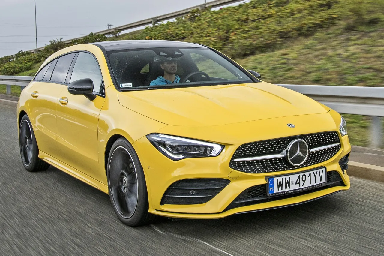Żółty Mercedes-Benz CLA Coupe mknie po drodze, kierowca w niebieskiej bluzie prowadzi auto.