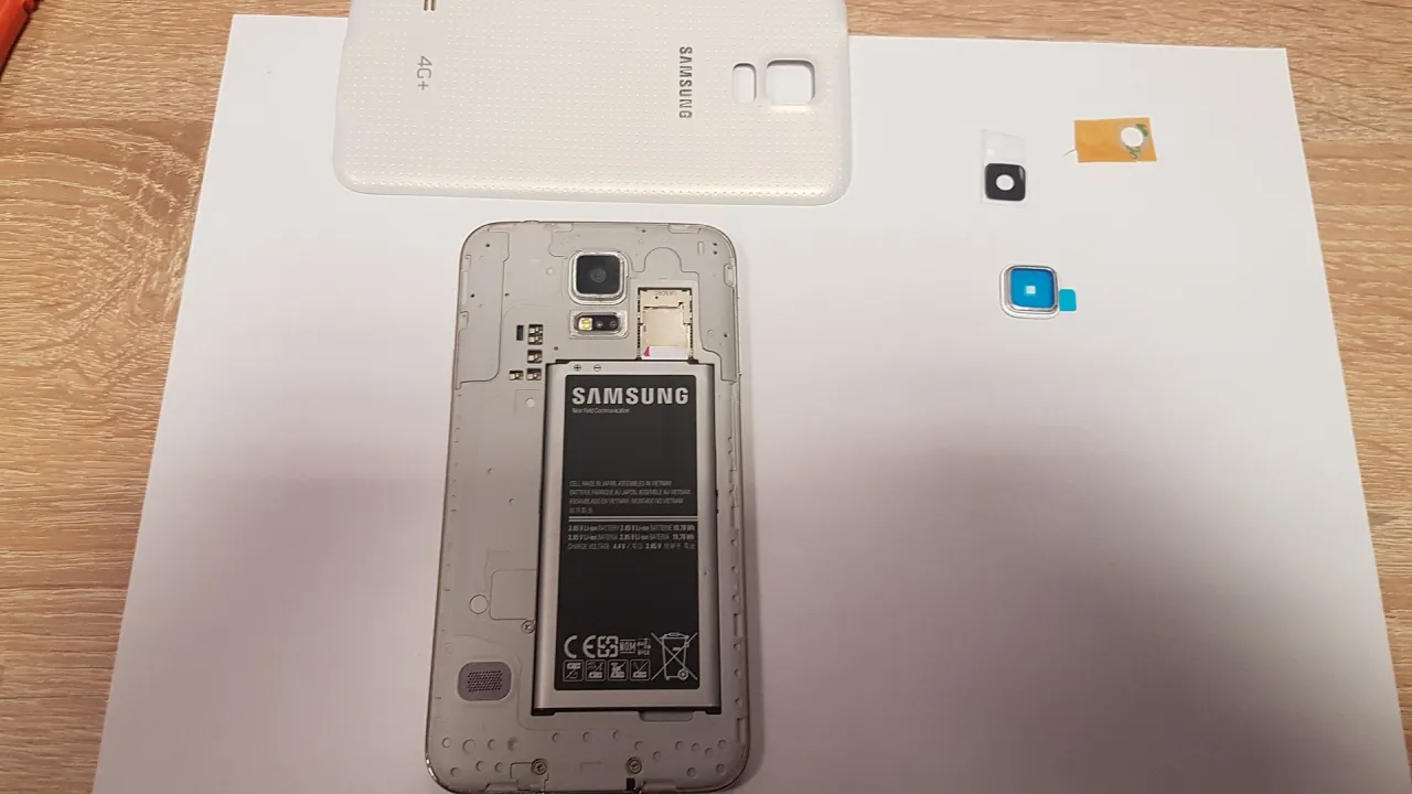 Rozłożony telefon Samsung z wyjętą baterią i nową szybką aparatu obok. Jak wymienić szybkę aparatu w telefonie?