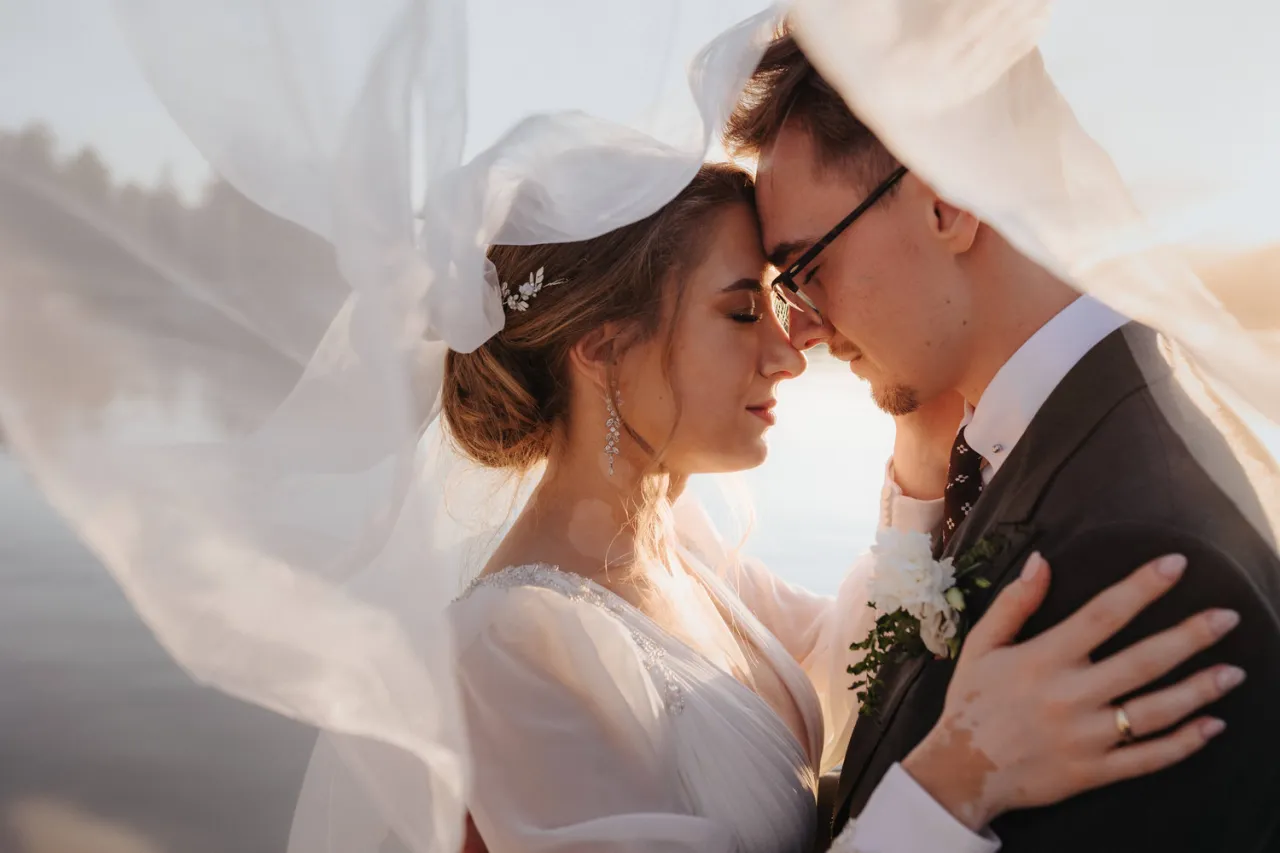 Para pięknie obejmuje się pod welonem. Warto ustalić z fotografem przed ślubem, jak uchwycić takie intymne chwile.