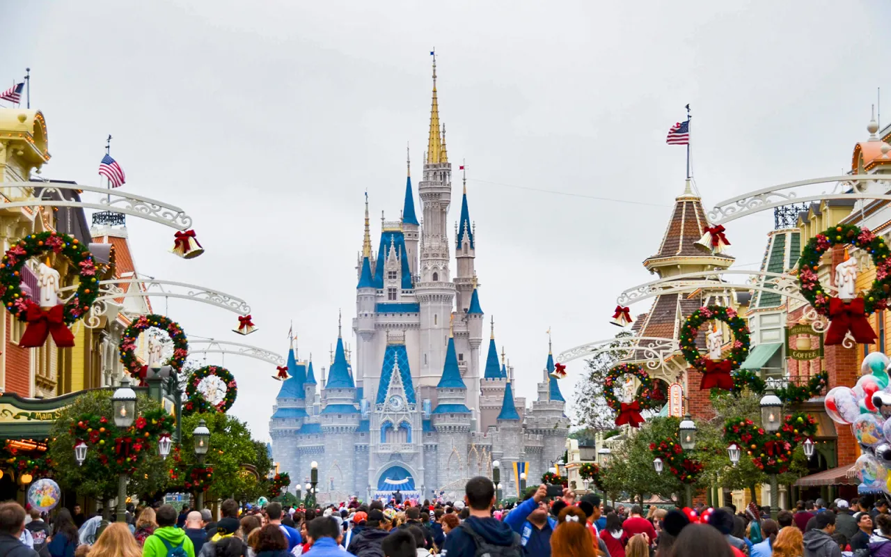 Tłum ludzi idzie ulicą w kierunku zamku, ozdobionego świątecznymi girlandami. To musi być Disneyland w Europie!