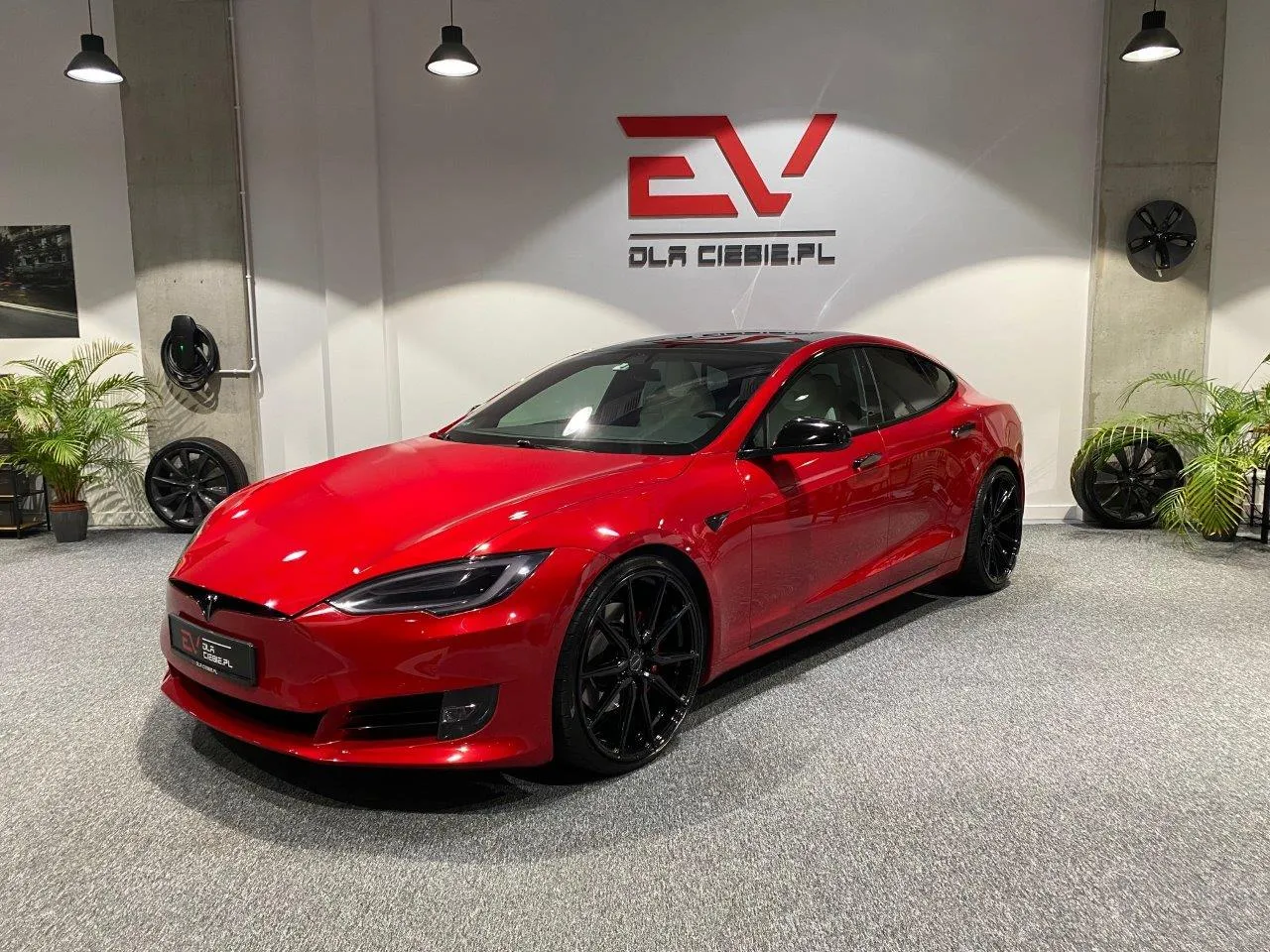 Błyszcząca, czerwona Tesla Model S na czarnych felgach. Zastanawiasz się, ile kosztuje Tesla Model S? Ten egzemplarz wygląda na wart fortunę!