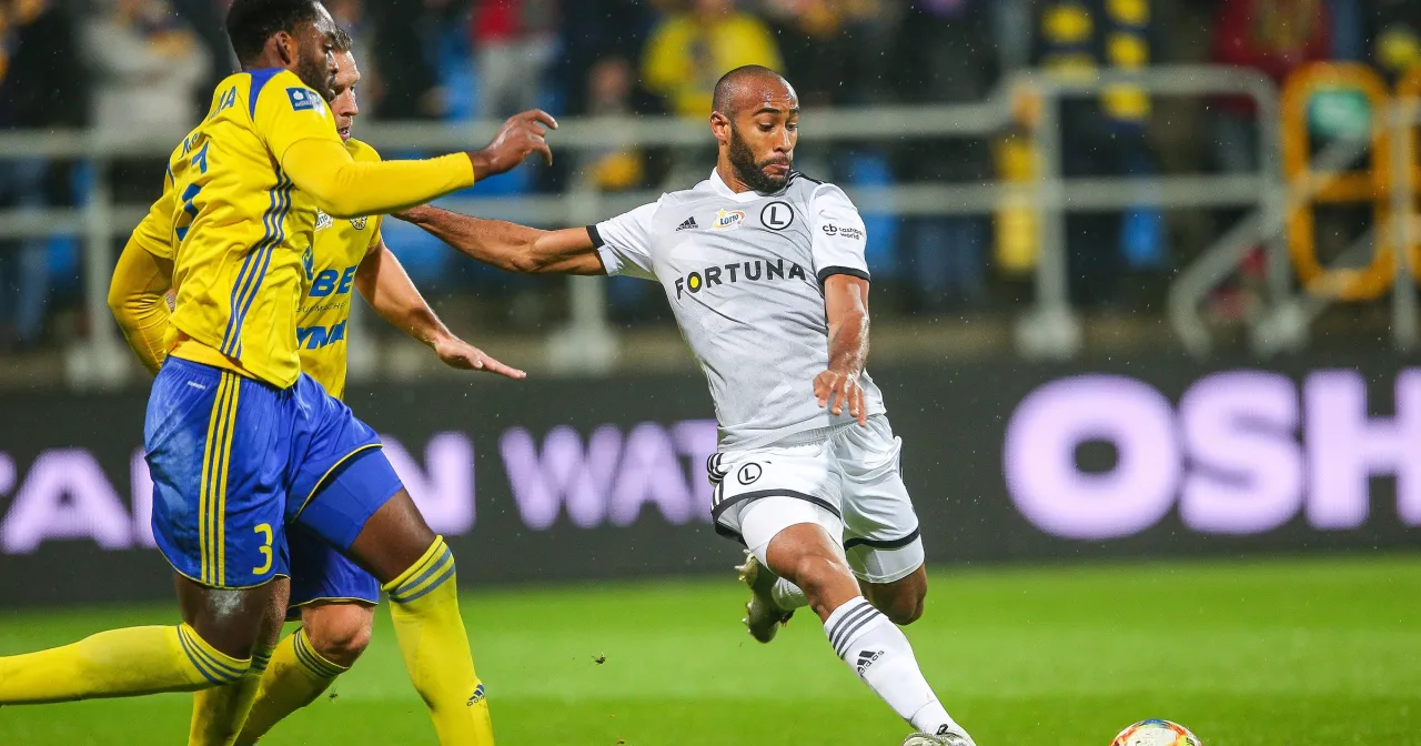 Piłkarz w białej koszulce z logo Fortuna drybluje, podczas gdy zawodnik w żółtej koszulce próbuje go zatrzymać. To mógł być ostatni mecz ekstraklasy.