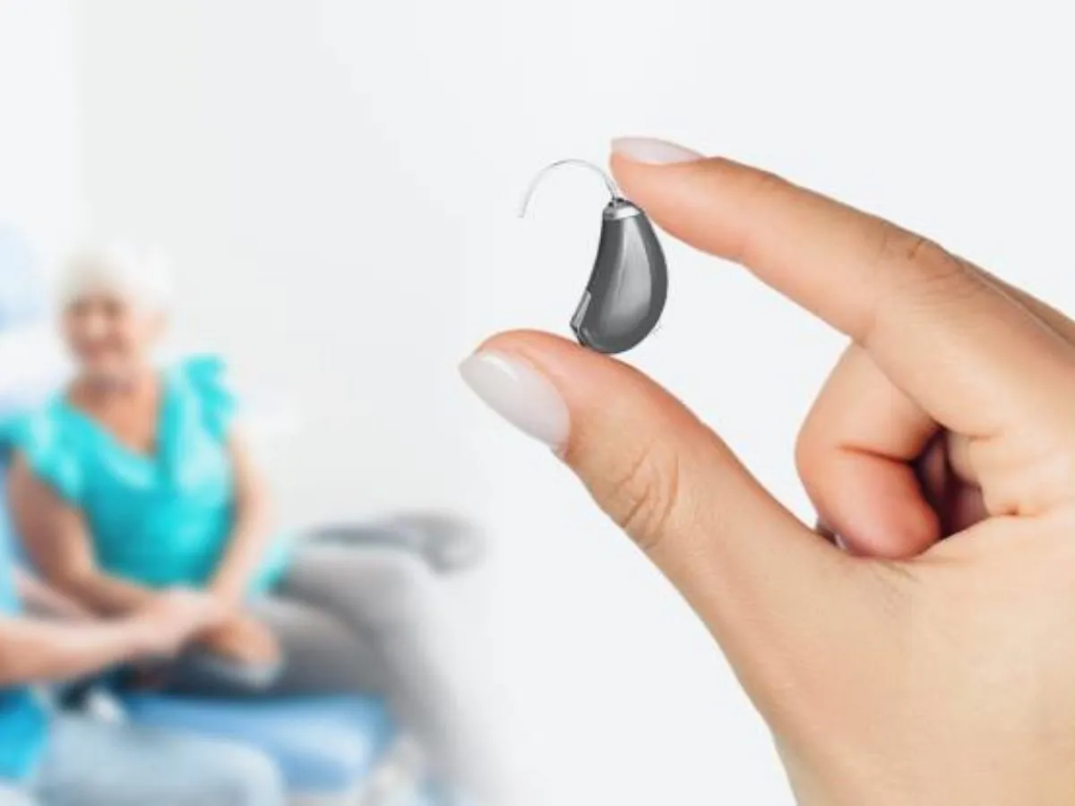 Dłoń trzyma aparat słuchowy. Zastanawiasz się, ile kosztuje aparat słuchowy?
