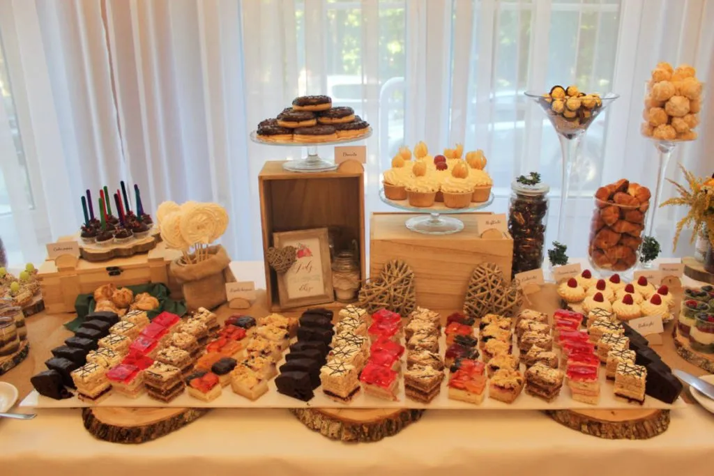 r&oacute;żnorodne ciasta na słodkim stole weselnym