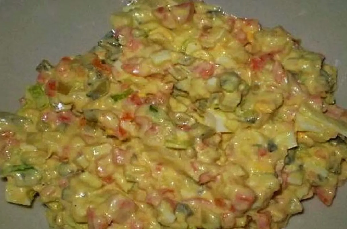 Sałatka jarzynowa z jogurtem zamiast majonezu. Widać kawałki jajek, warzyw i ogórków.