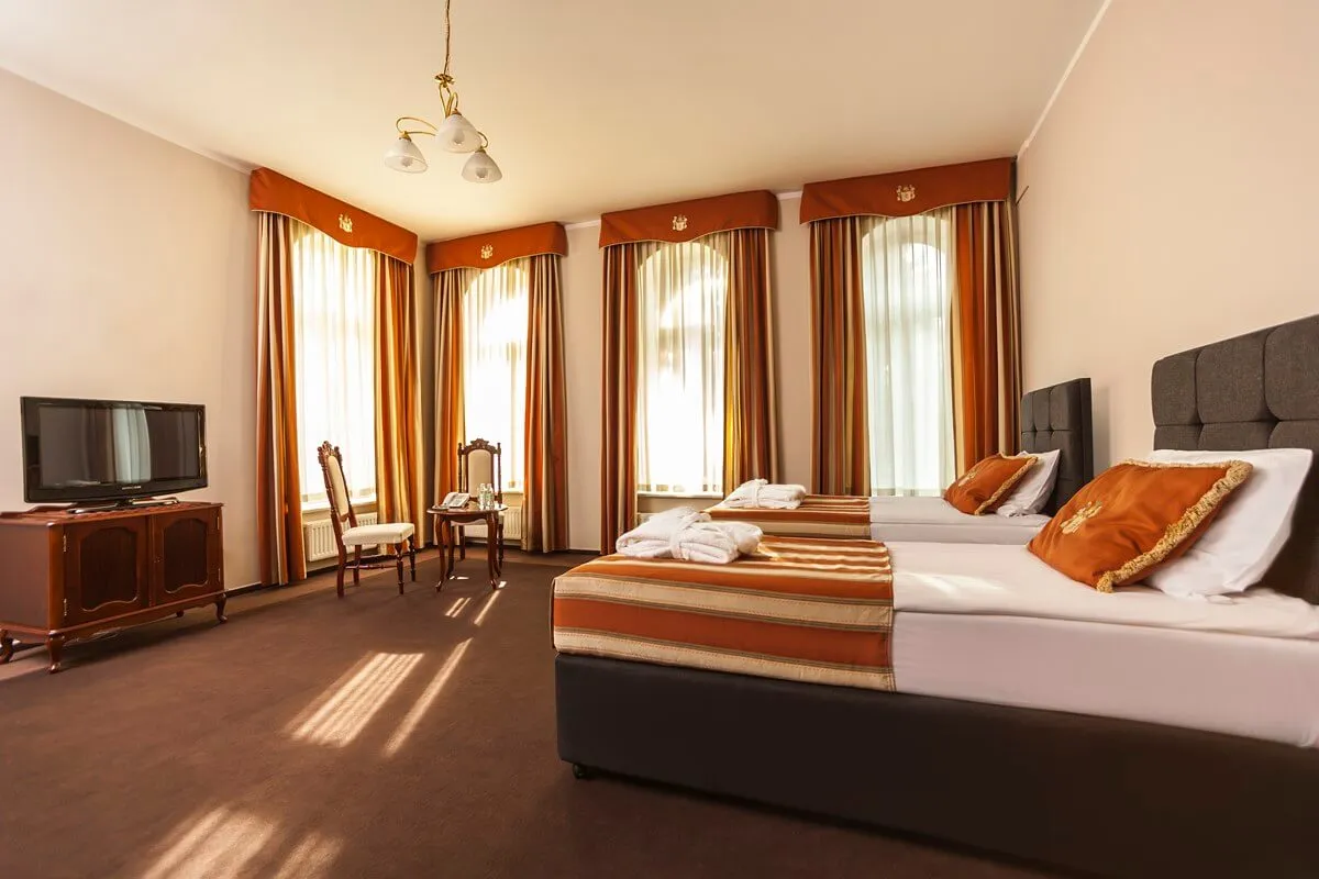 Pokój w sanatorium z dwoma łóżkami, szlafrokami i widokiem na okna. Zastanawiasz się, jaki wybrać pokój w sanatorium?