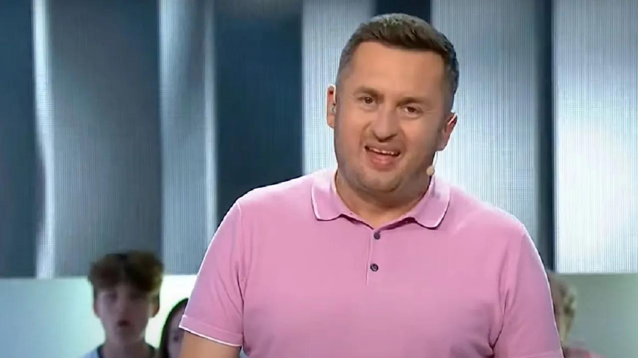 Norbi w r&oacute;żowej koszulce polo, uśmiechnięty, w tle młodzi ludzie. Ciekawe, ile zarabia Norbi w Kole Fortuny?