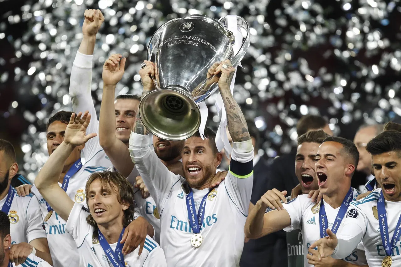 Piłkarze Realu Madryt świętują zdobycie Ligi Mistrz&oacute;w 2022, unosząc puchar wśr&oacute;d konfetti.