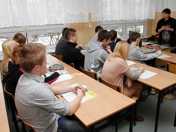 nauczyciel historii pomaga uczniowi przy biurku w klasie