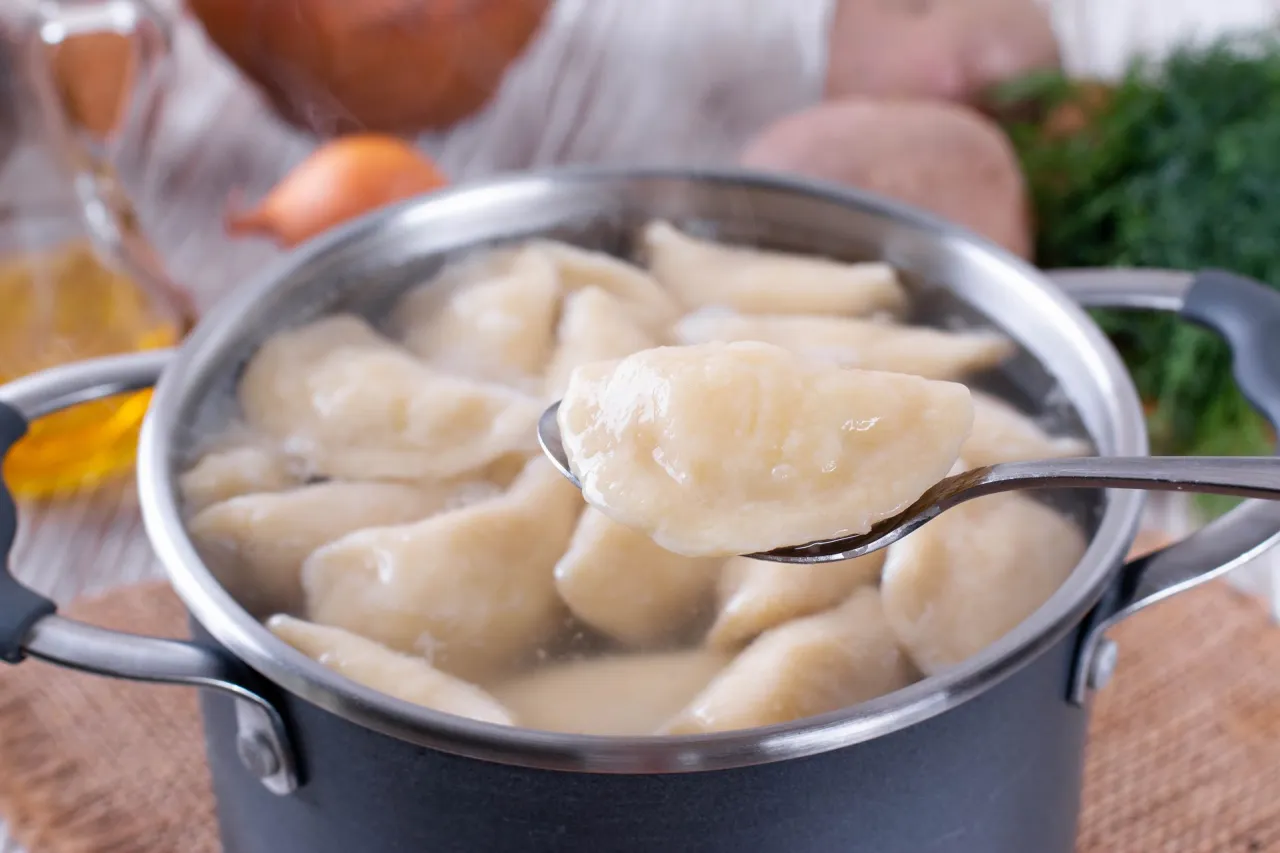 Gotujesz pierogi ruskie w garnku. Łyżka podnosi jednego, by sprawdzić, czy są gotowe do zamrożenia.