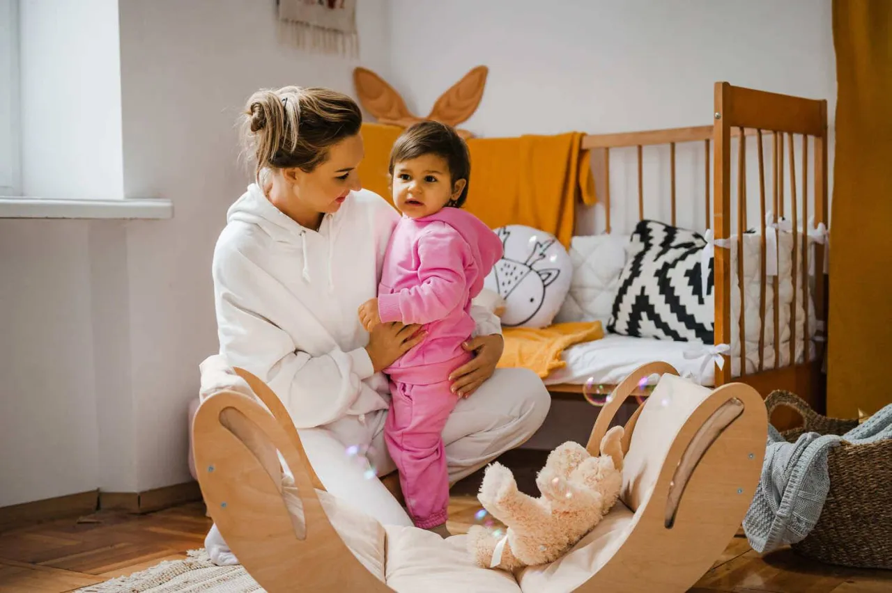 Rodzic i dziecko budujące wieżę z klock&oacute;w, uśmiechnięci, w uporządkowanym pokoju