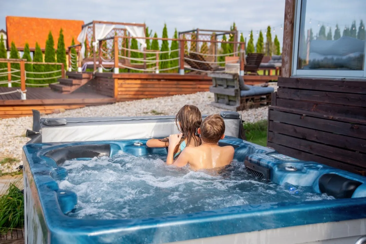 Dzieci kąpią się w jacuzzi, relaksując się w domku spa na Mazurach.
