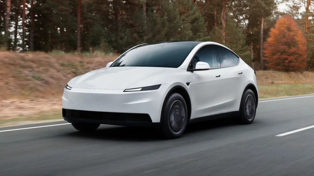 Biała Tesla pędzi przez jesienny las. Przyspieszenie do 100 km/h to dla niej chwila.