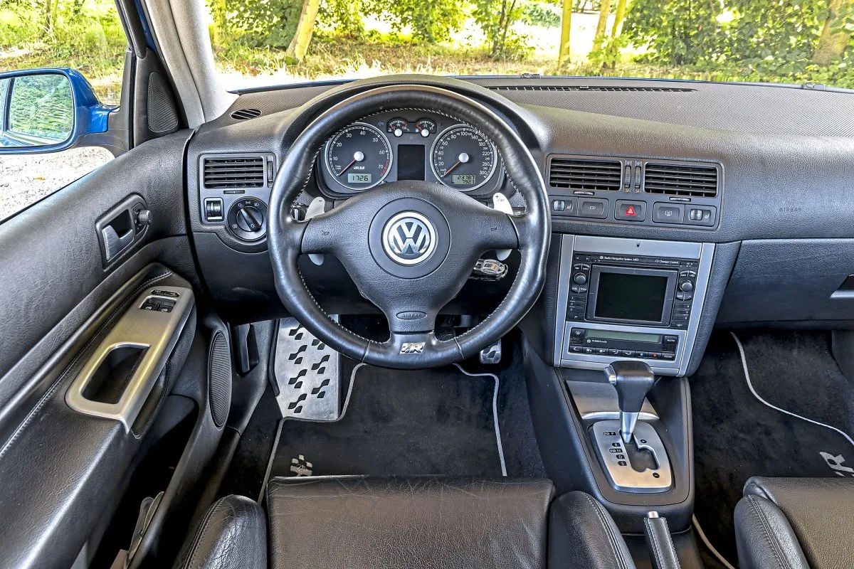 Wnętrze Golfa R32 z czarną tapicerką, kierownicą z logo VW i oznaczeniem R, automatyczną skrzynią biegów i radiem.