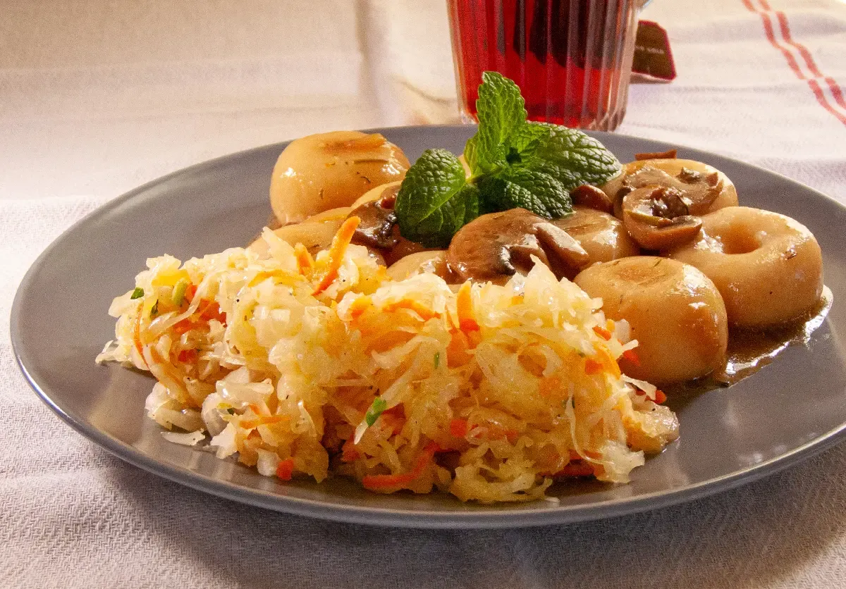 Surówka z kapusty kiszonej z marchewką, podana z duszonymi pieczarkami i ziemniakami. Idealne co dodać do surówki z kapusty kiszonej dla smaku.