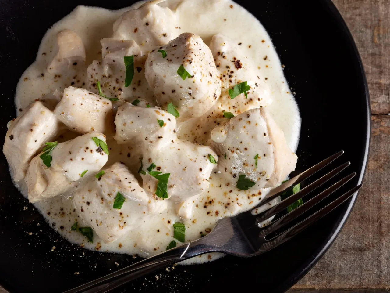 Kawałki piersi z kurczaka w kremowym sosie, posypane pieprzem i natką pietruszki. Idealny pomysł na to, jaki sos do piersi z kurczaka.