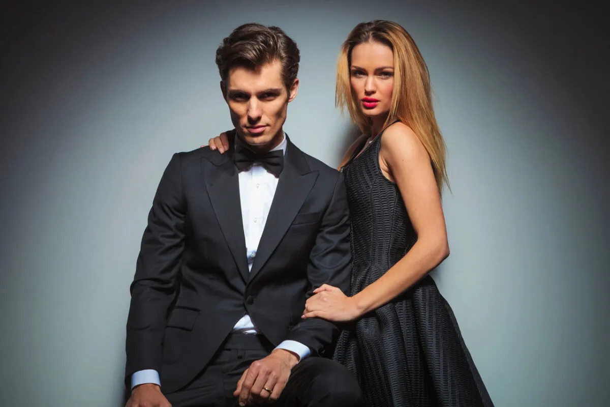 Elegancka para, on w smokingu, ona w czarnej sukience. Idealny przykład, jak się ubrać do teatru, by zrobić wrażenie.