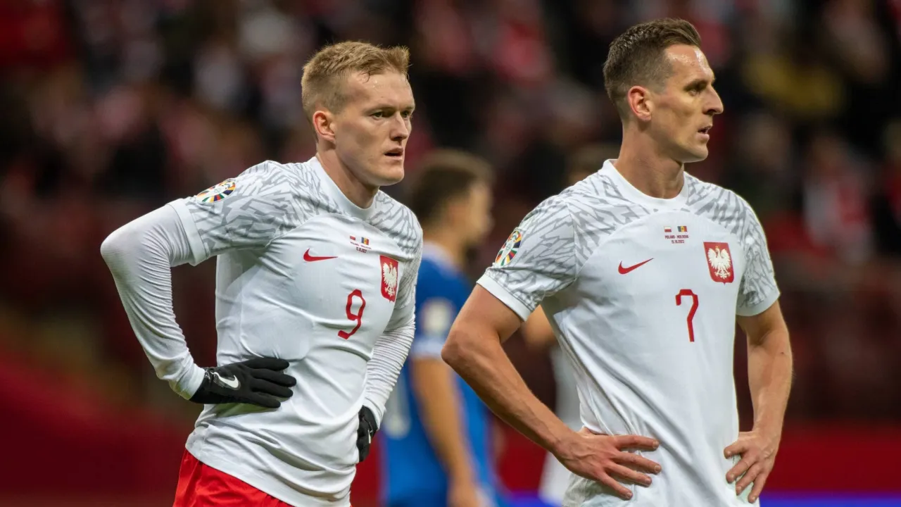 Dw&oacute;ch piłkarzy reprezentacji Polski w białych strojach z orłem na piersi, z numerami 9 i 7.