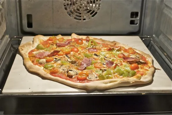 Pizza casera horneándose sobre piedra de pizza en un horno