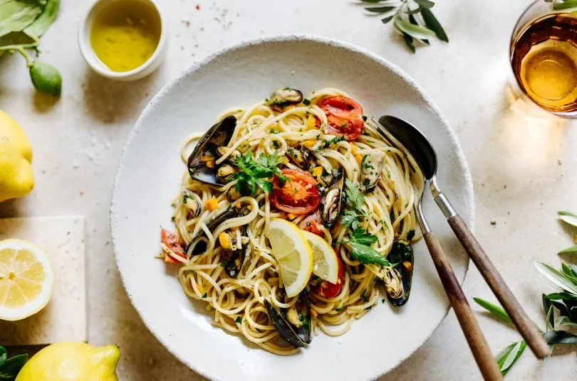 Pasta mit Muscheln professionell angerichtet mit Petersilie und Zitrone