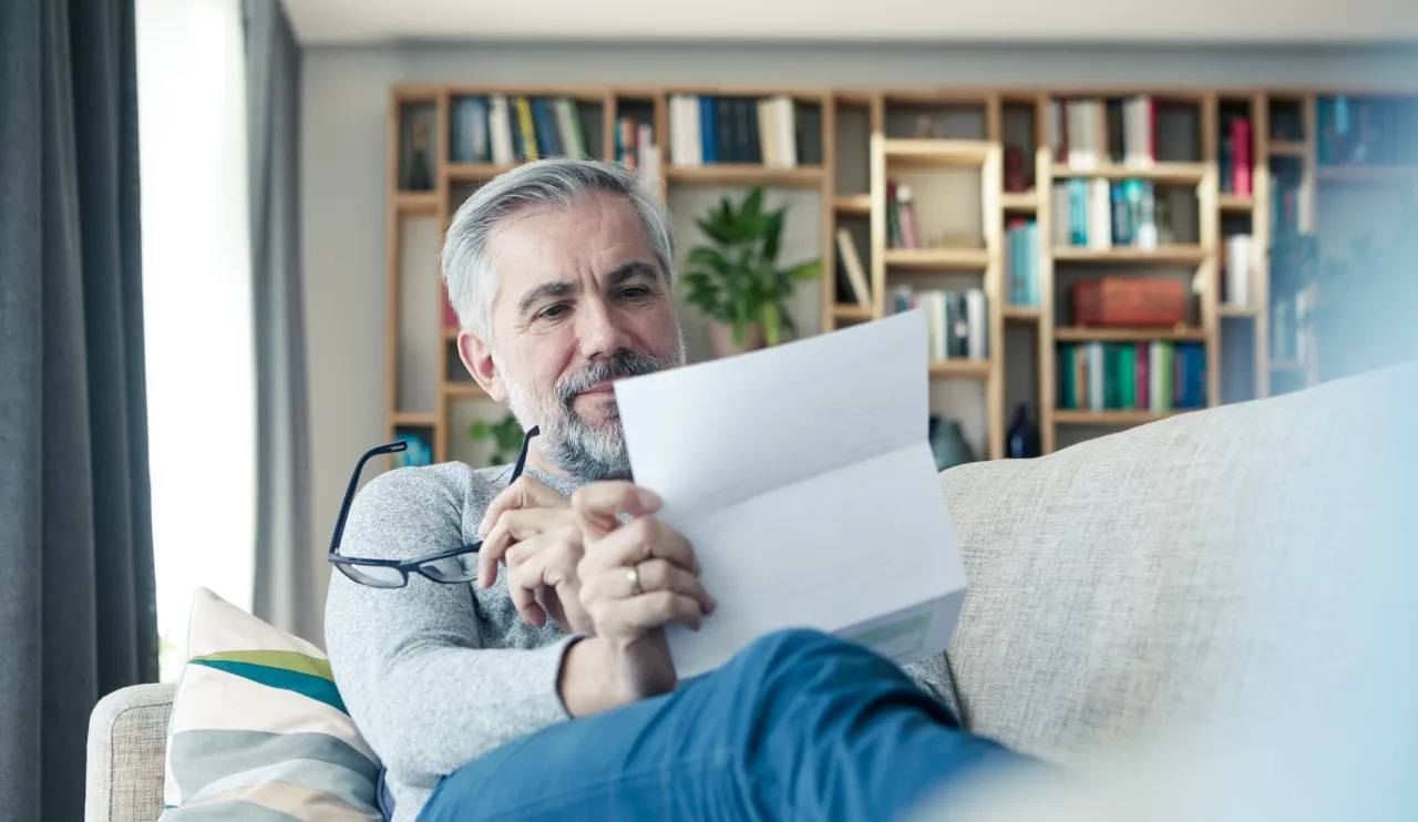 Mężczyzna czyta dokument, szukając informacji o ubezpieczeniowym funduszu gwarancyjnym jak uniknąć kary.