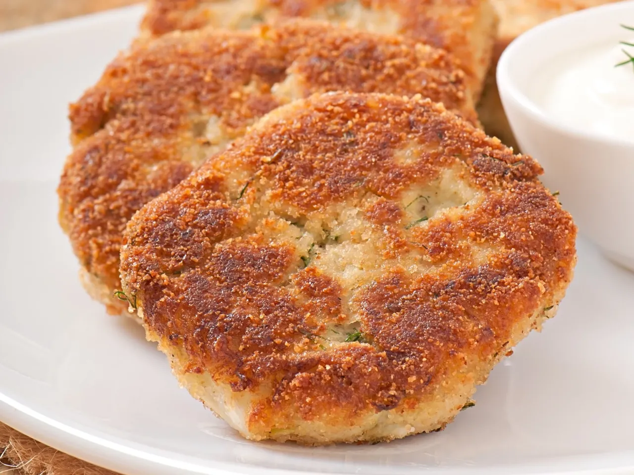 Złociste kotleciki ziemniaczane, idealne na co na obiad w Wielką Sobotę, podane z sosem.