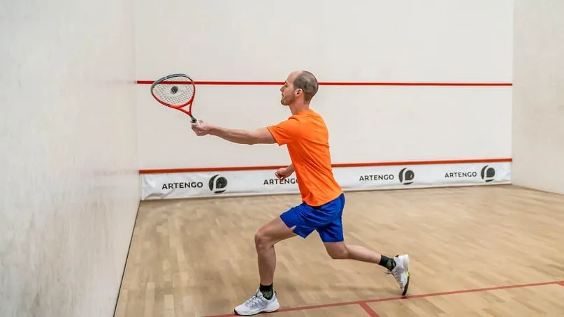 osoba grająca w squasha, dynamiczne ujęcie, kort, rakieta, piłka