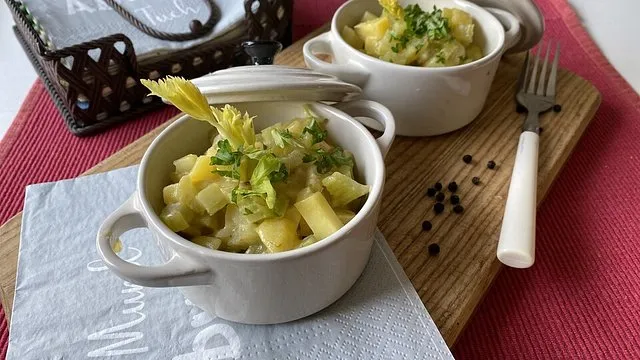 gew&uuml;rfelter Stangensellerie Kartoffeln und Zwiebeln auf einem Holzbrett