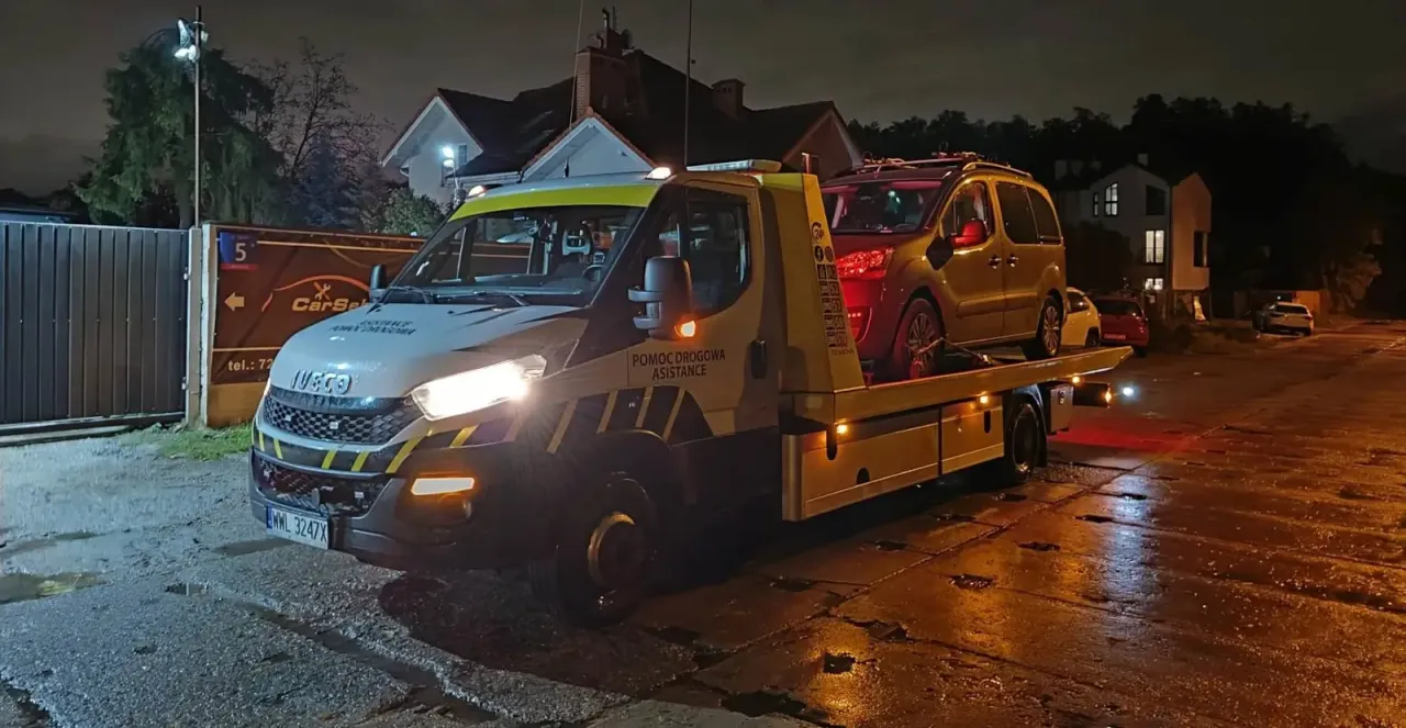 Pomoc drogowa assistance to ratunek w potrzebie. Holownik z załadowanym autem nocą, gdy liczy się szybka reakcja.