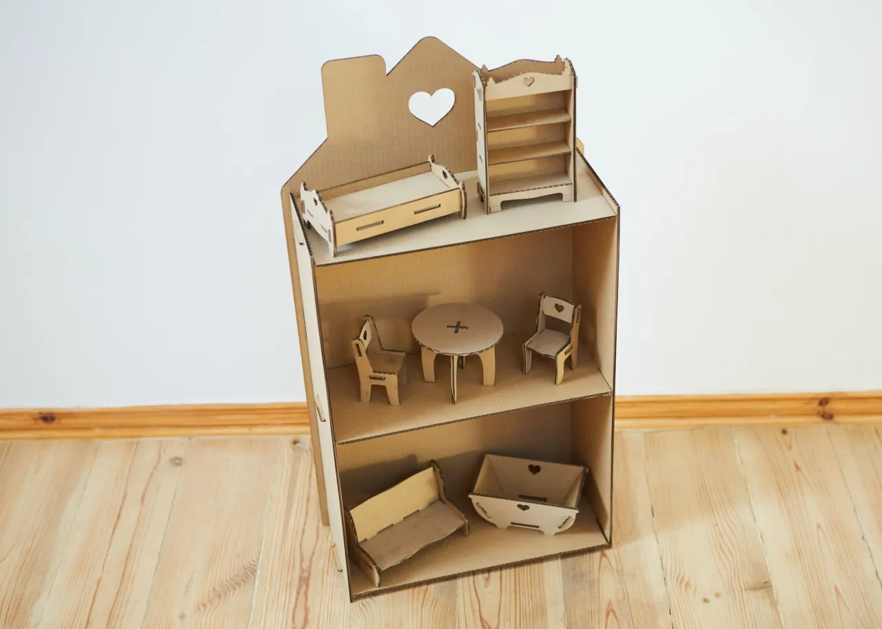 Kartonowy domek dla lalek DIY z mebelkami: łóżko, szafka, stół z krzesłami, kanapa i skrzynia.