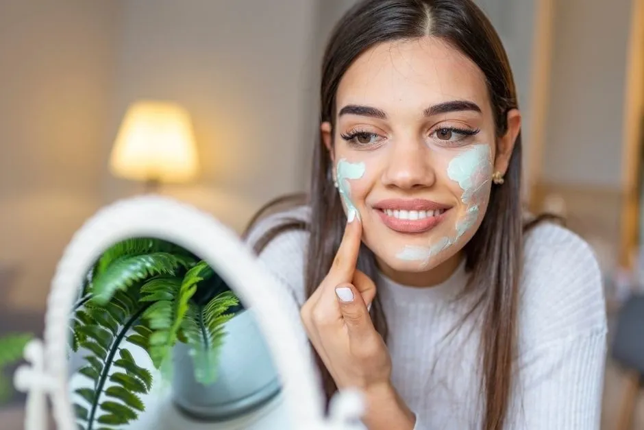 kobieta nakładająca zielony korektor na twarz