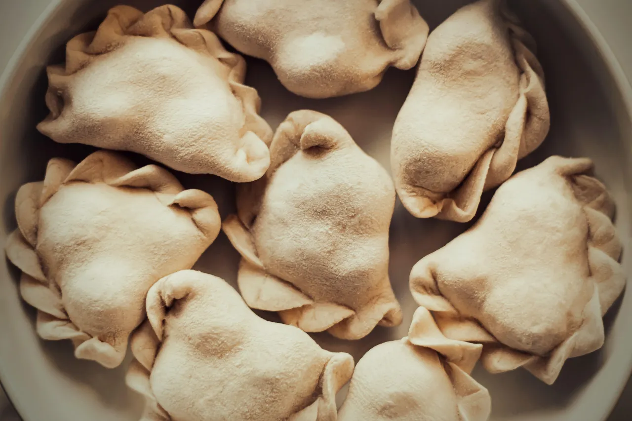 Surowe pierogi w misce. Zastanawiasz się, czy płukać pierogi po ugotowaniu? Te wyglądają apetycznie!