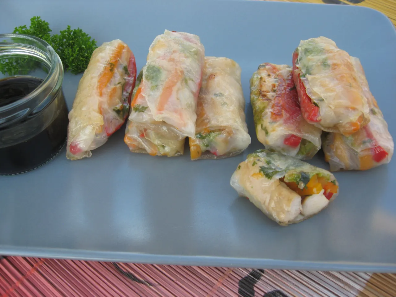 Świeże sajgonki z kurczakiem i kolorowymi warzywami, podane z sosem.