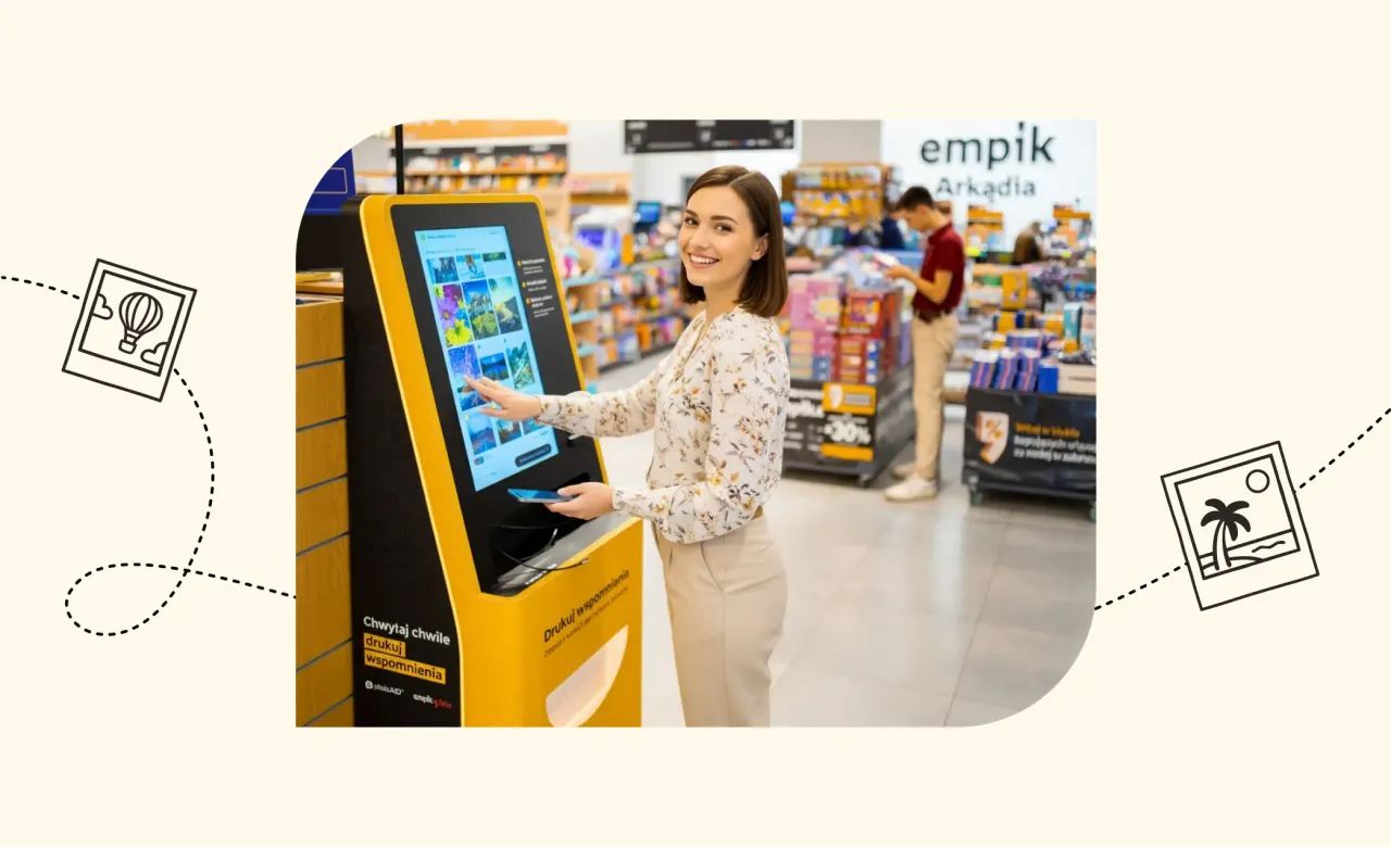 Kobieta korzysta z kiosku Empik, by wydrukować zdjęcia od ręki. Na ekranie widać galerię zdjęć, a obok znajduje się telefon.