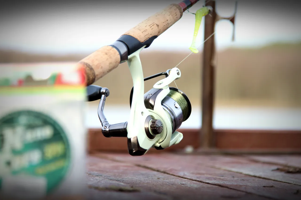 Kołowrotek spinningowy z zieloną żyłką i gumową przynętą. Zastanawiasz się, jaka grubość żyłki na spinning będzie najlepsza?