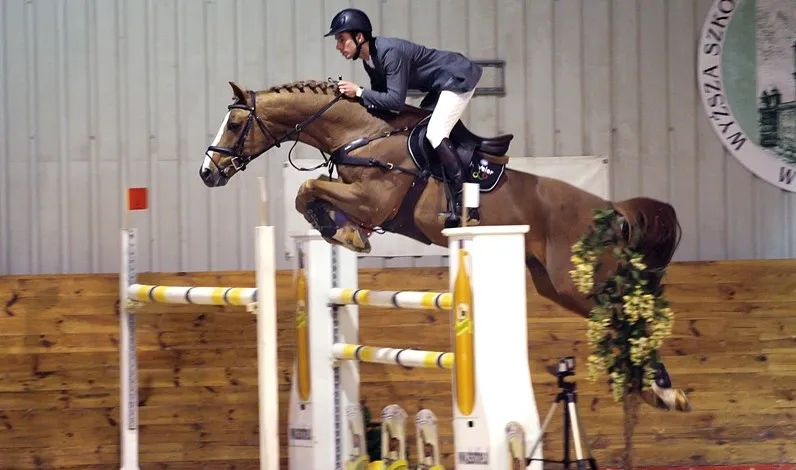 Jeździec i koń skaczący przez niską przeszkodę