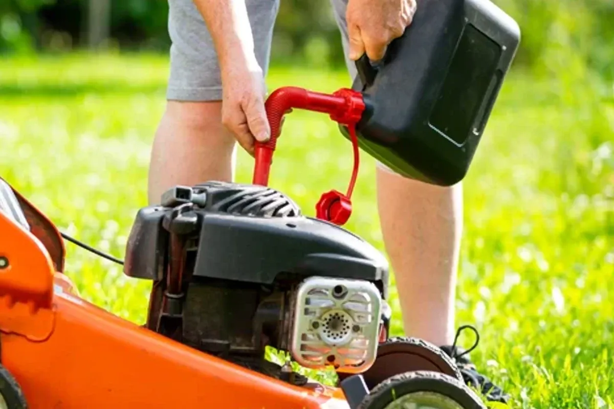 Osoba nalewa paliwo do kosiarki Briggs & Stratton. Używa do tego czerwonego lejkawka.